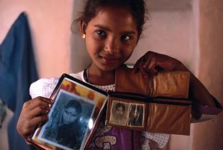 A girl showing photos of her mother who died in child birth.