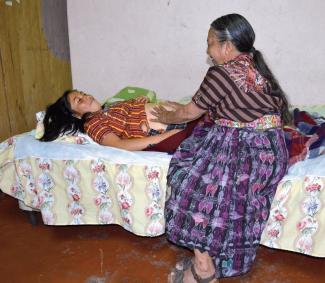 A traditional midwife in Guatemala examines a pregnant woman.