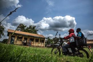A Kenyan health worker delivers vaccines in a cool box on a motorcycle.