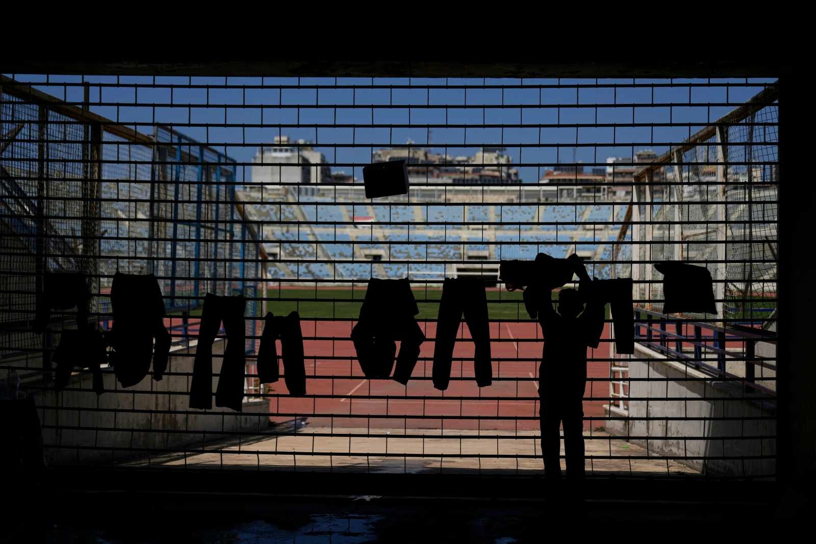A boy is hanging up laundry at Beirut’s Camille Chamoun Sports City Stadium, which has been converted into an emergency shelter for refugees.