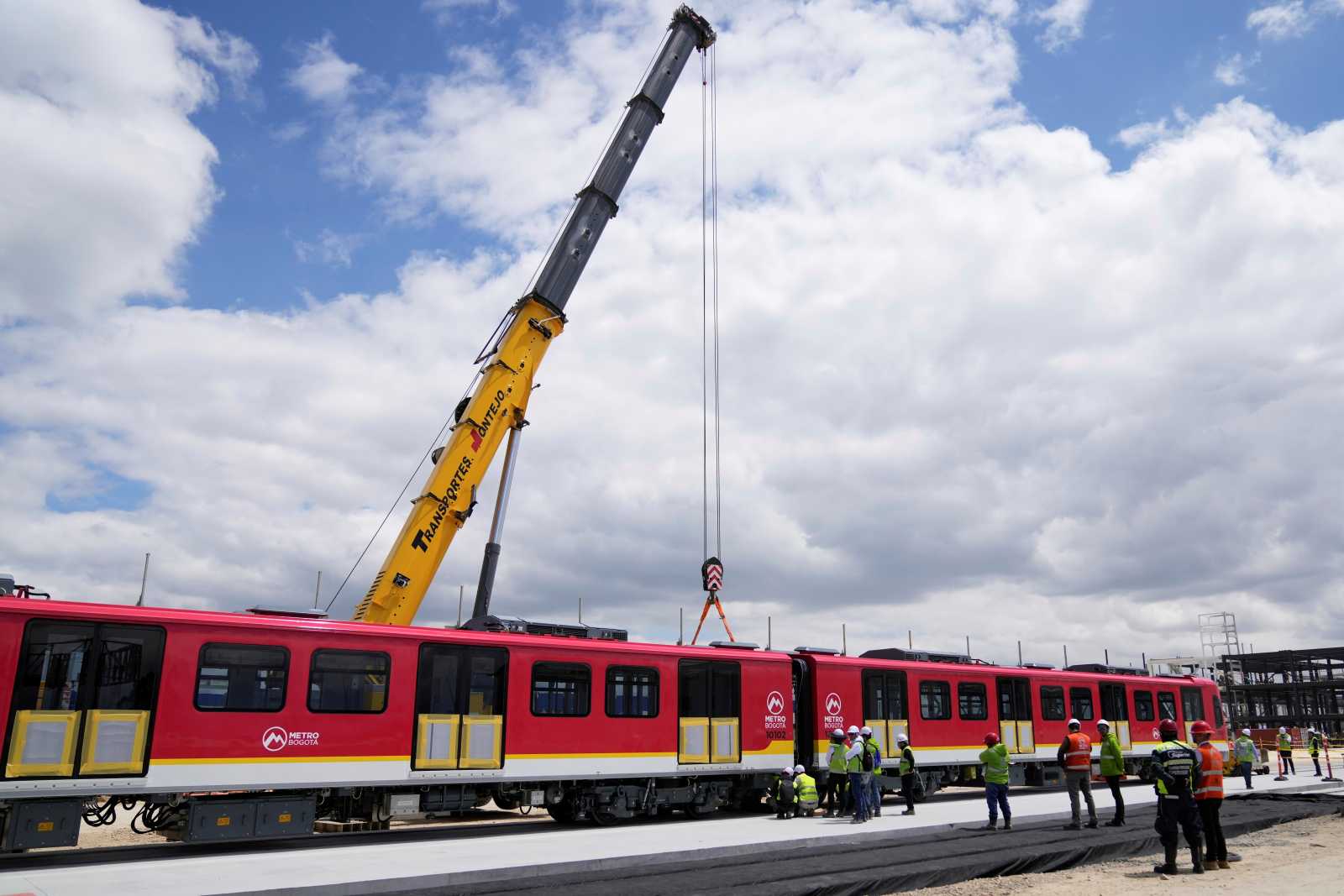 Workers supervise the unloading of metro train cars in Bogota, after disembarking from China, in September 2025.