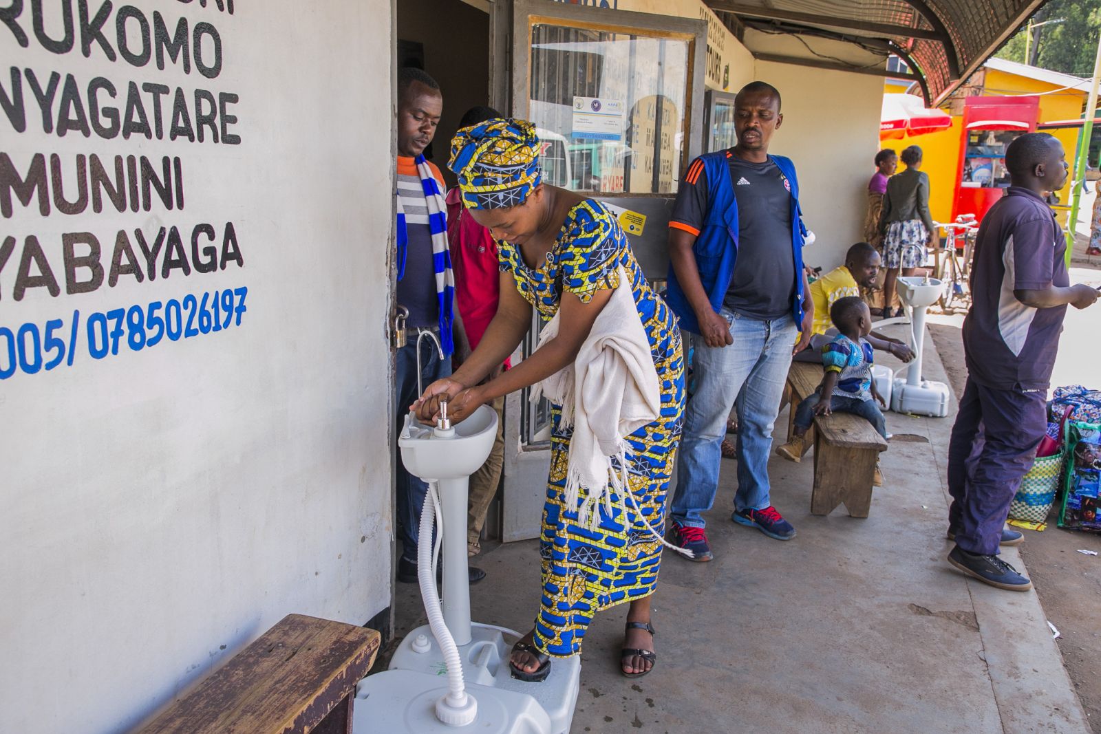 A woman washing her hands before entering a bus ticket office in Kigali, Rwanda.
