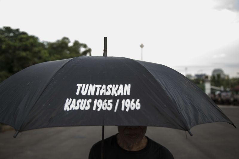 Donal Husni/picture-alliance/NurPhoto Making a statement in Jakarta: the writing on the umbrella means: “Resolve the 1965/1966 case.”