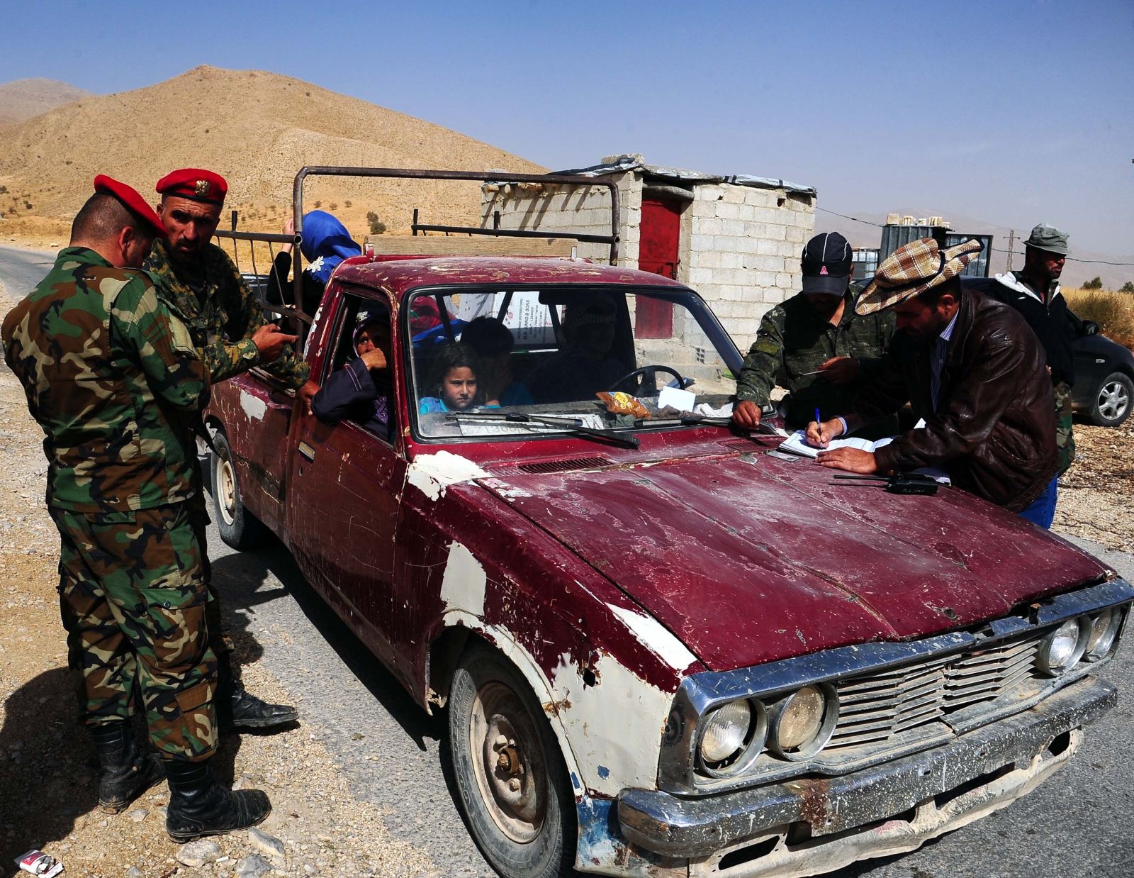 picture-alliance/Photoshot Syrische Soldaten am Grenzübergang Zamrani kontrollieren die Papiere von Geflüchteten, die aus dem Libanon nach Syrien zurückkehren.