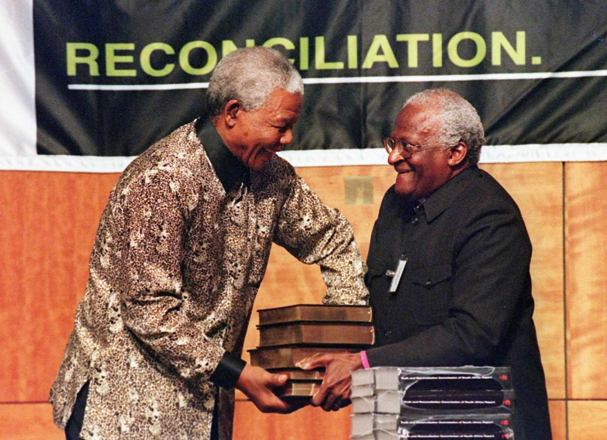 Nelson Mandela receives the five volumes of South Africa's Truth and Reconciliation Commission final report from its chairperson Archbishop Desmond Tutu in 1998