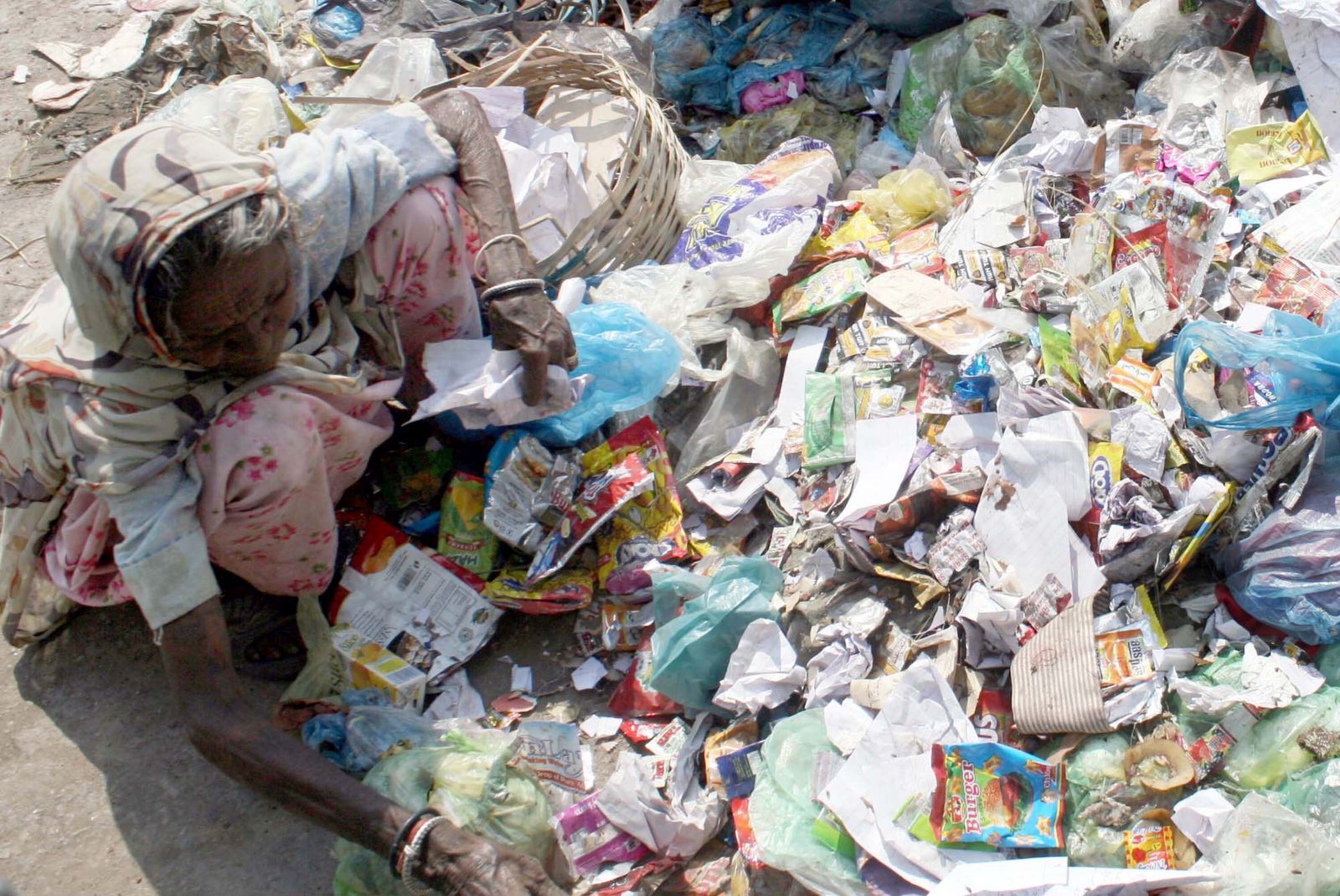 S.Imran Ali/picture-alliance/Asianet Pakistan Mittellose Frau sortiert Plastikmüll auf einer Straße in Karachi.