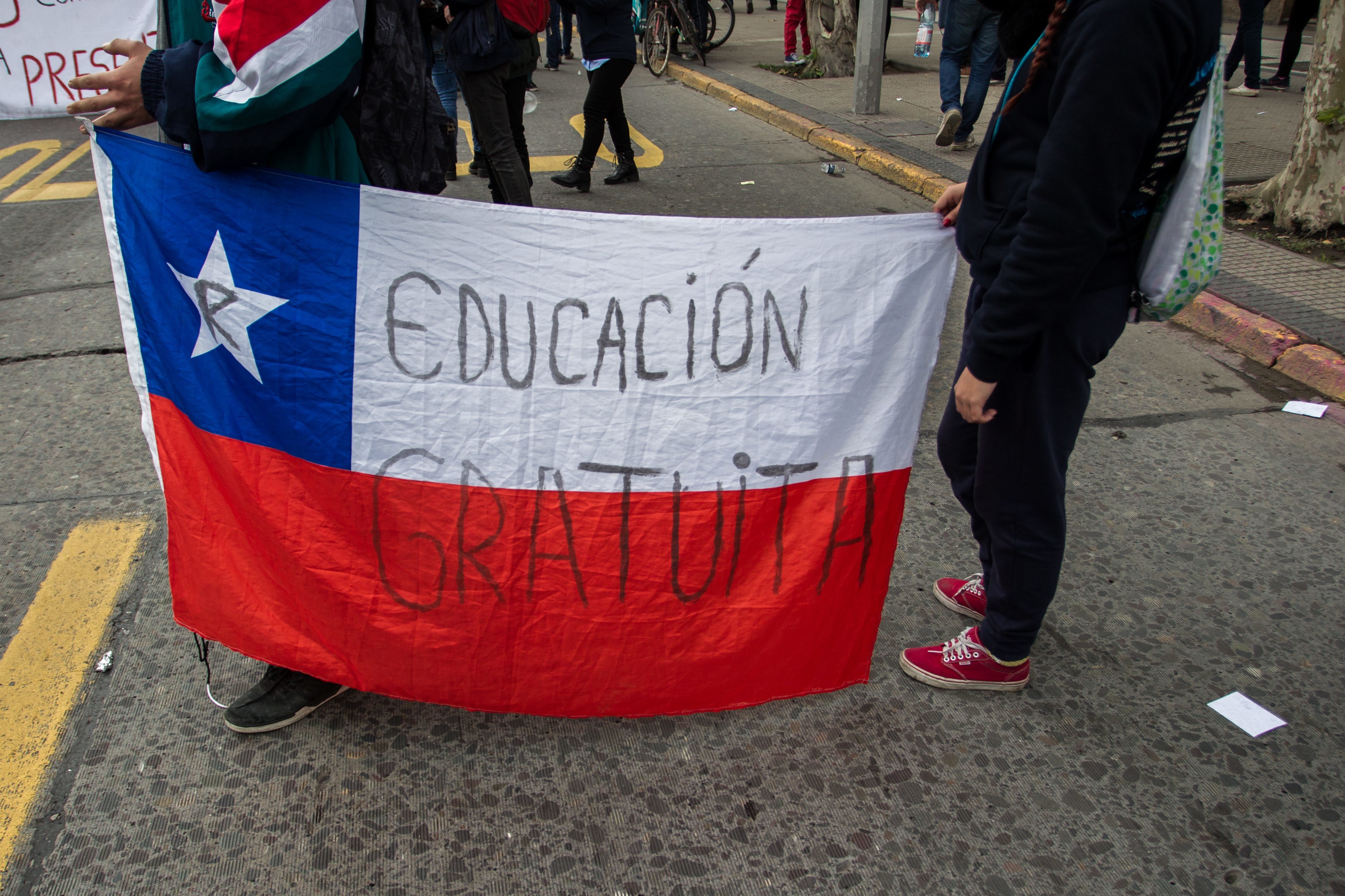 Gomez/picture-alliance /NurPhoto Two protesters hold a Chilean flag with the slogan “free education” (in Spanish) in Santiago in June 2016.