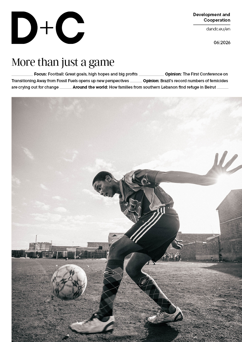 Black-and-white “D+C” magazine cover (06/2026) headlined “More than just a game,” featuring a footballer on a dusty pitch winding up to strike the ball.