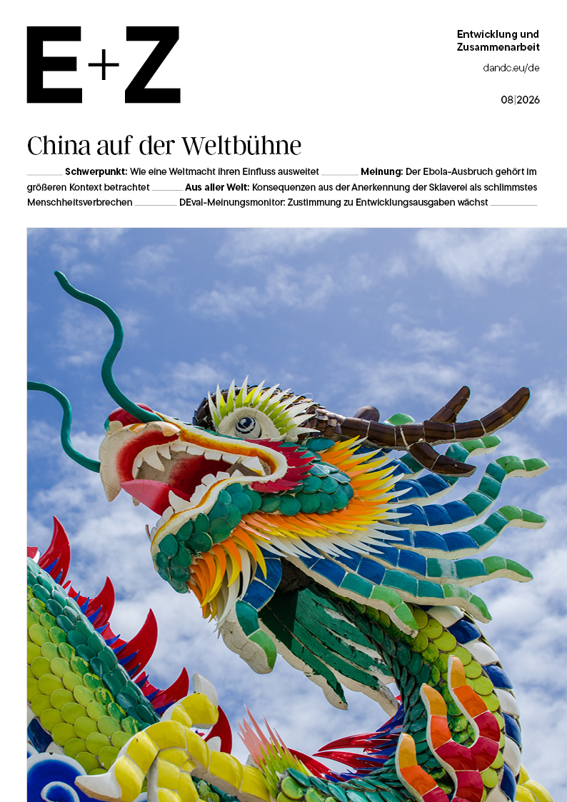 Bunte chinesische Drachenfigur mit geöffnetem Maul und grünen Schuppen vor blauem Himmel mit Wolken.