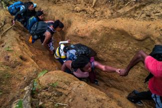 Migrant*innen aus Haiti und Ecuador zwängen sich im November 2022 durch einen schmalen Pfad im Dschungel des Darién Gap.