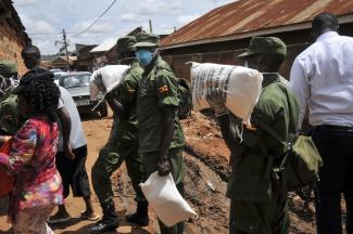 Soldaten liefern Maismehl an Bedürftige in einem Vorort Kampalas aus.