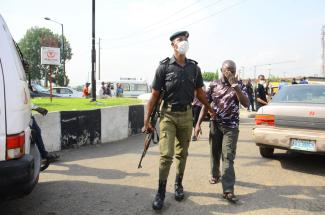Nigerian police officer arresting man for disobeying lockdown.
