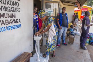 A woman washing her hands before entering a bus ticket office in Kigali, Rwanda.