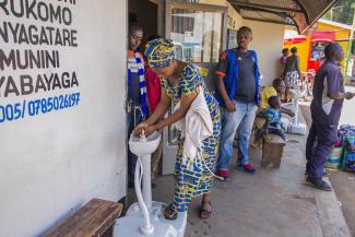 picture-alliance/XinHua Eine Frau in Kigali, Ruanda, wäscht sich die Hände, ehe sie eine Busticket-Verkaufsstelle betritt.