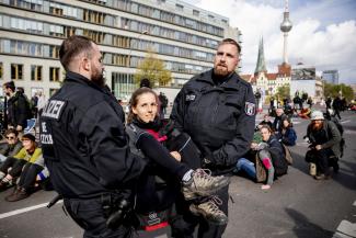 Police officers carrying an XR protester away from a bridge in Berlin.