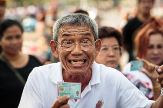 Unable to cast their votes, angry citizens display identity cards in Bangkok.