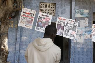 Schlagzeilenlektüre an einem Zeitungsstand in Dakar im Sommer 2009.