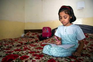 No interaction possible: third-grader taking notes while watching Tele-School TV at home in Islamabad in 2021.