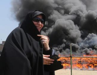 An Iranian woman watches confiscated drugs being burned in Tehran in 2013.