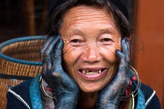 Frau der Hmong-Ethnie in Vietnam, die vom Färben schwarze Hände hat. Die Hmong-Dörfer sind beliebtes Ziel chinesischer Touristen.