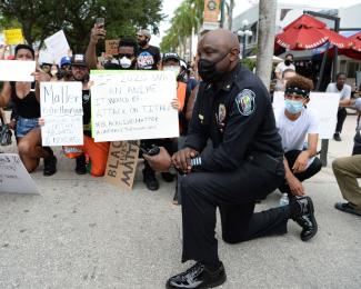 picture-alliance/mpi04/MediaPunch Police officer taking a knee with Californian anti-racism activists.